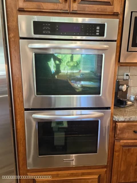 Stainless steel double oven installed in a wooden cabinet by certified technicians.